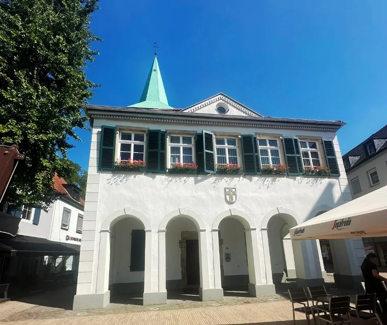 Das Alte Rathaus in Dorsten, umgeben von Kopfsteinpflaster und umrahmt von blauen Himmel, zeigt traditionelle Bauweise und Baustruktur.